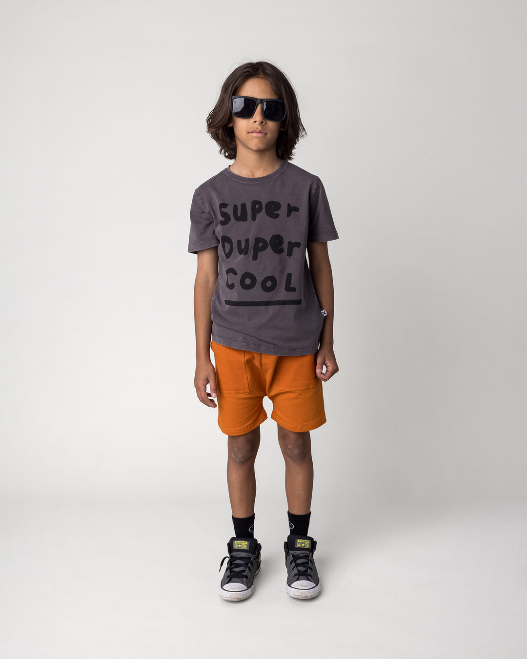 Kid wearing the Super Duper Cool Tee in black wash with the Rib Pocket Short in burnt orange, front view