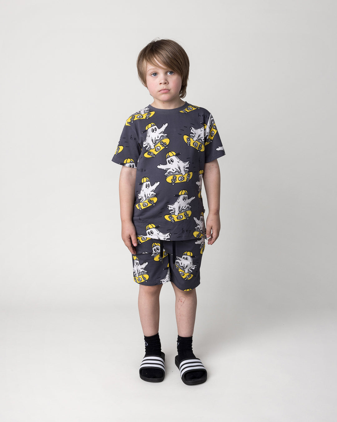 Kid wearing the Skate Ghost Tee in dark grey with the Skate Ghost Short in dark grey, front view