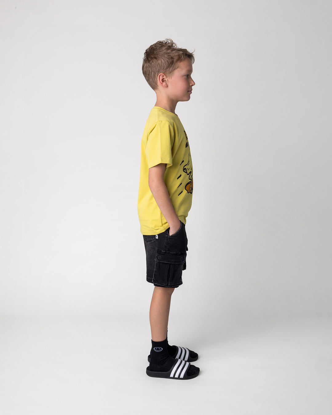 Kid wearing the Skate Ghost Tee in zest, side view