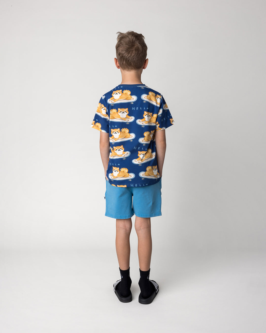Kid wearing the Skate Puppy Tee in midnight with the Blasted Track Short in sky wash, back view