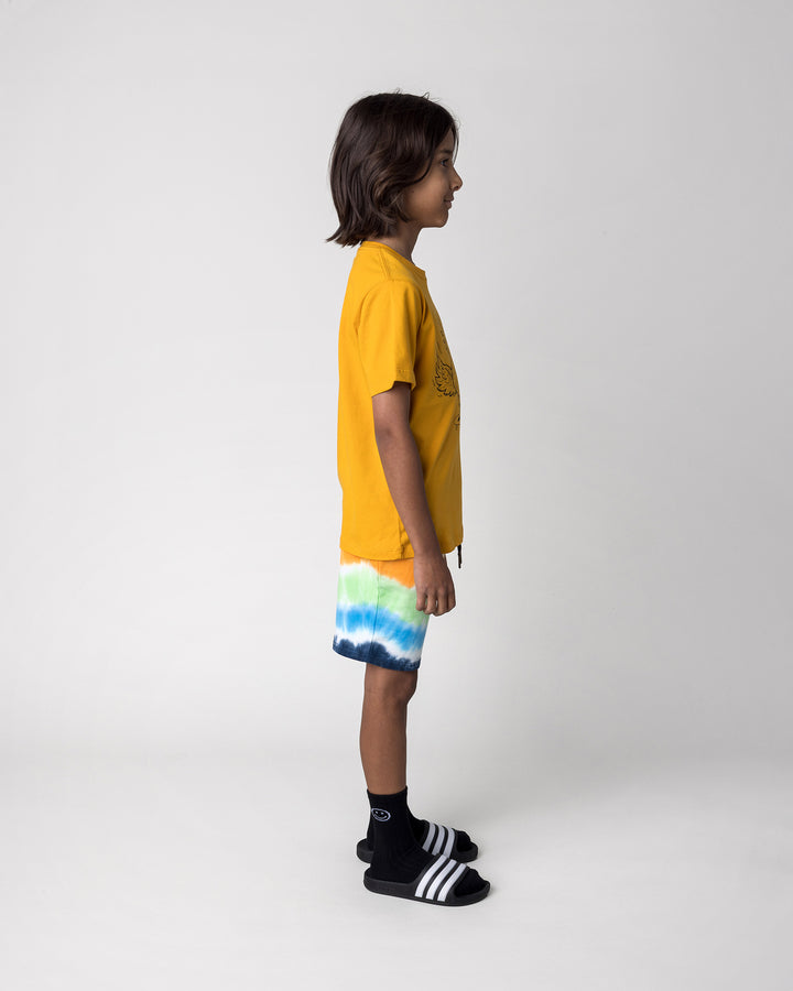 Kid wearing the Skate Phoenix Tee in mustard with the Airwaves Short in navy, side view