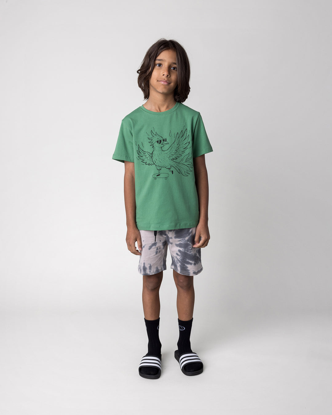 Kid wearing the Skate Phoenix Tee in turf with the Splatter Short in grey, front view