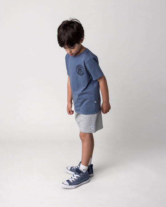 Kid wearing the Stay Cool Tee in blue wash with the Smile Short in grey marle, side view