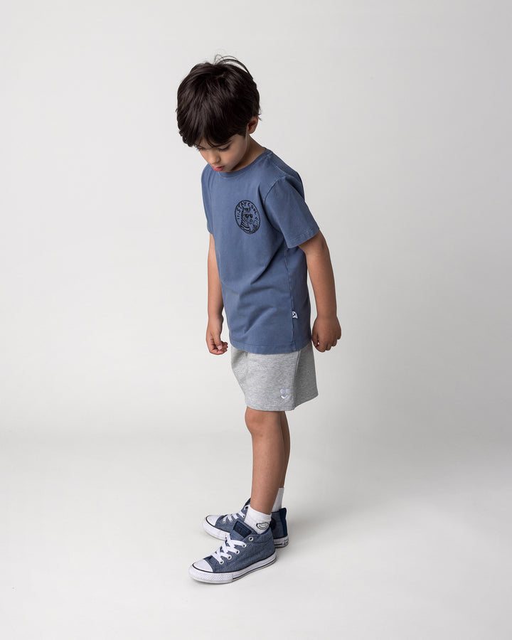 Kid wearing the Stay Cool Tee in blue wash with the Smile Short in grey marle, side view