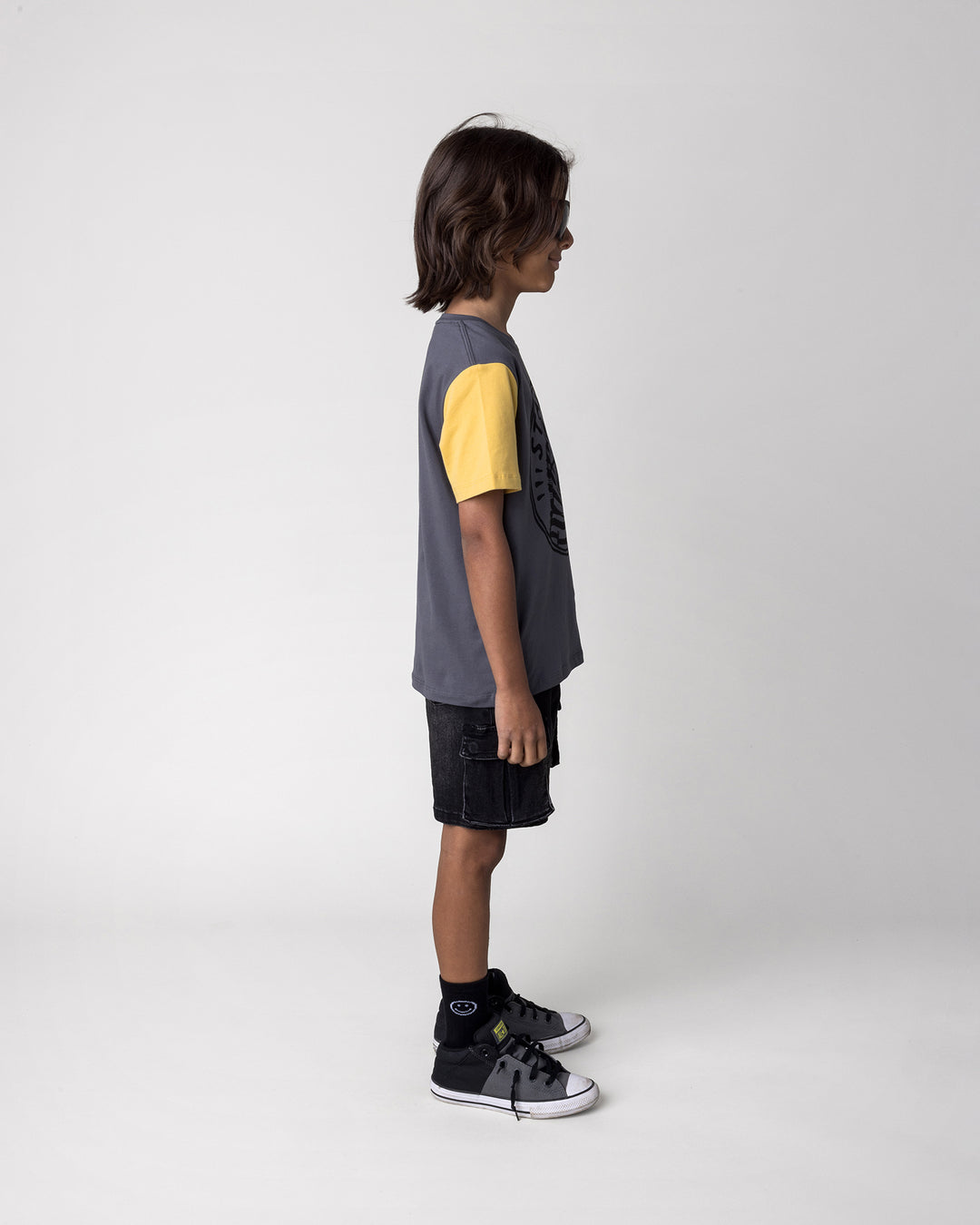 Kid wearing the Stay Cool Tee in dark grey, yellow and melon, side view