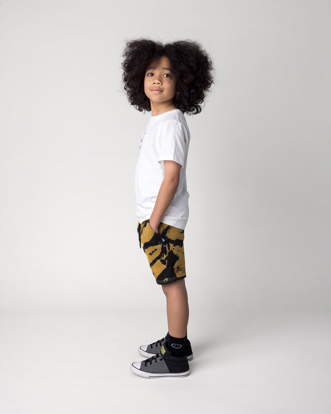 Kid wearing the Super Cool Tee in off white with the Duo Tie Dye Short in lemon and rust, side view
