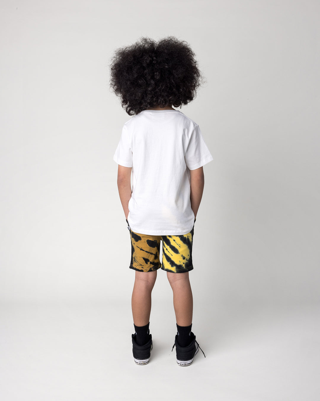 Kid wearing the Super Cool Tee in off white with the Duo Tie Dye Short in lemon and rust, back view