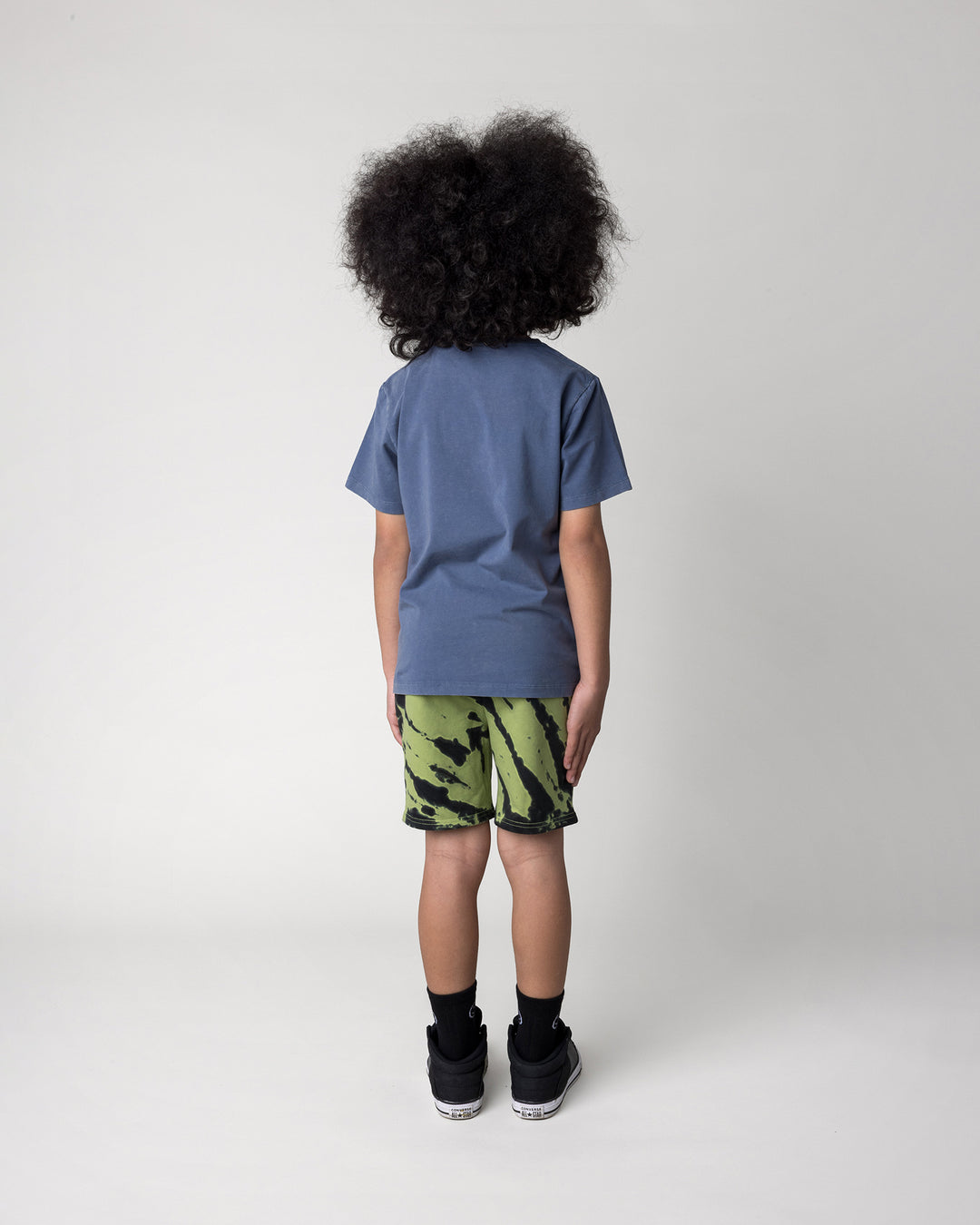 Kid wearing the Werewolf Rockstar Tee in blue wash with the Strike Short in lime, back view