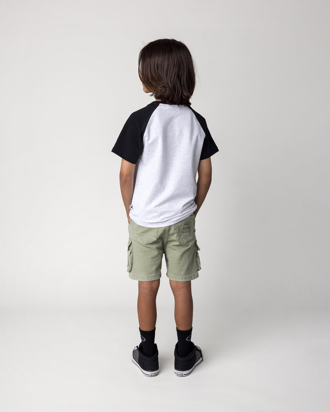 Kid wearing the Cool Dino Tee in white marle and black, back view