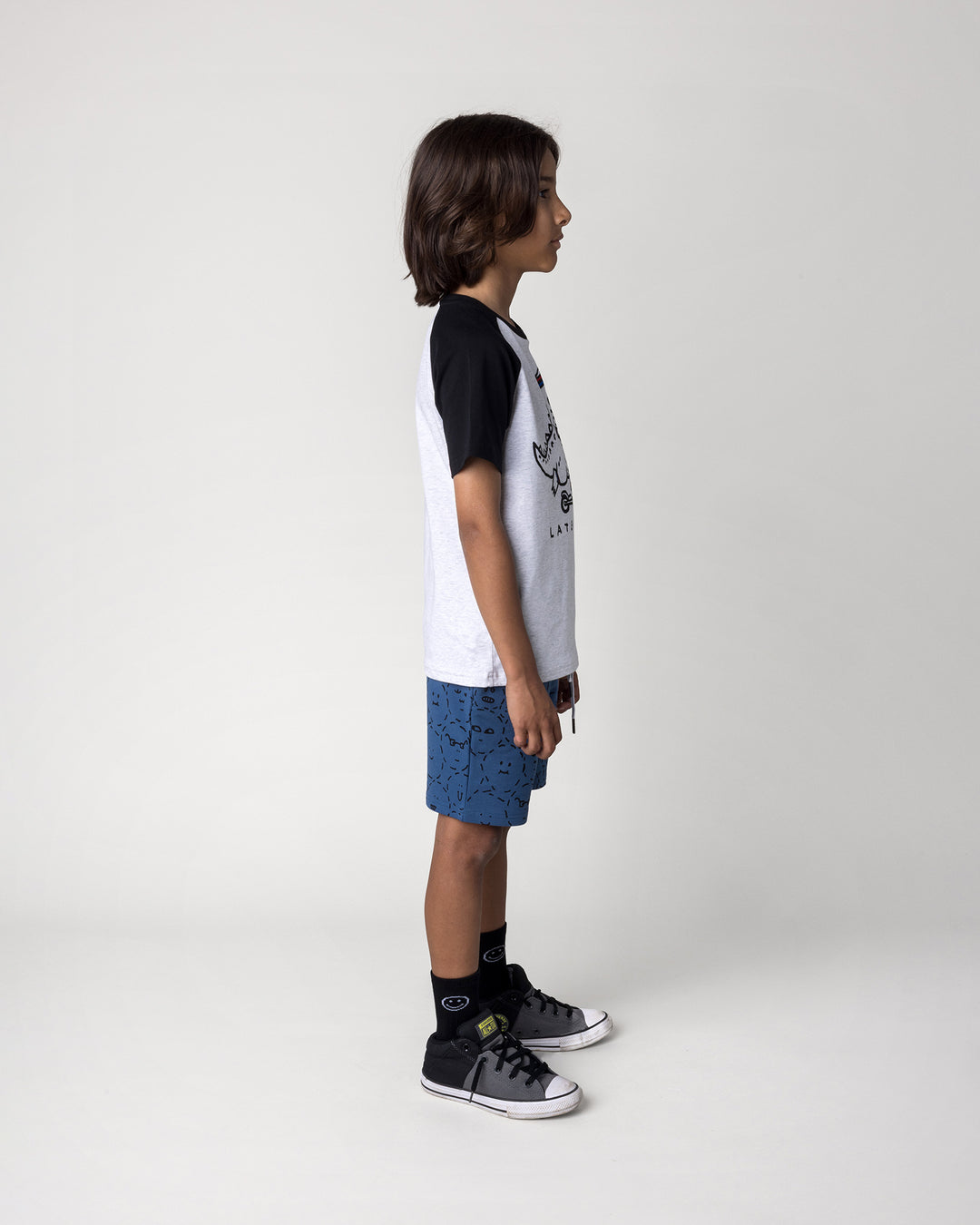 Kid wearing the Later Gator Tee in white marle and black with the Different Faces Short in midnight, side view