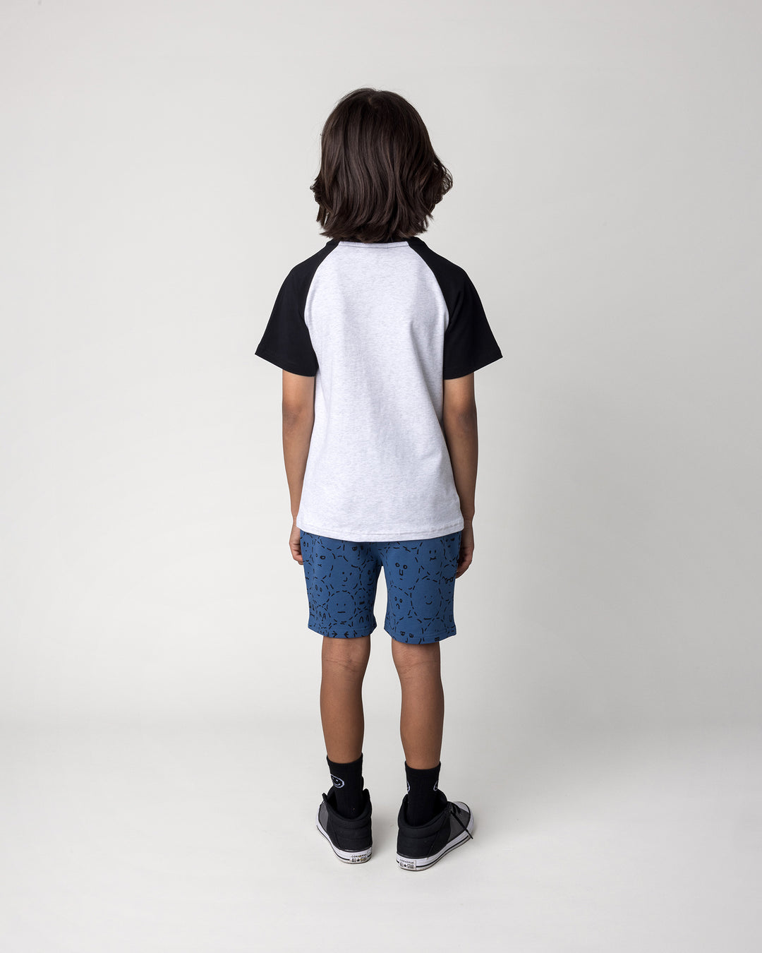 Kid wearing the Later Gator Tee in white marle and black with the Different Faces Short in midnight, back view