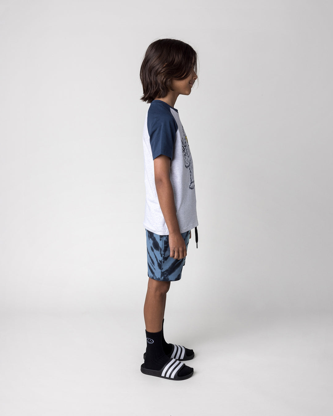 Kid wearing the Yo Yeti Tee in white marle and ink with the Duo Tie Dye Short in blue and aqua, side view