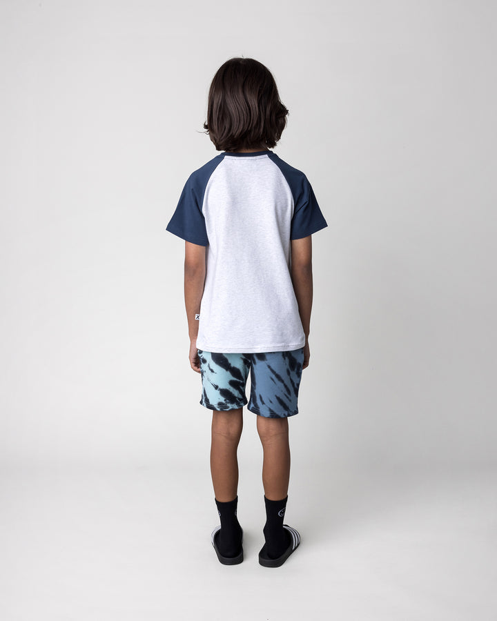 Kid wearing the Yo Yeti Tee in white marle and ink with the Duo Tie Dye Short in blue and aqua, back view