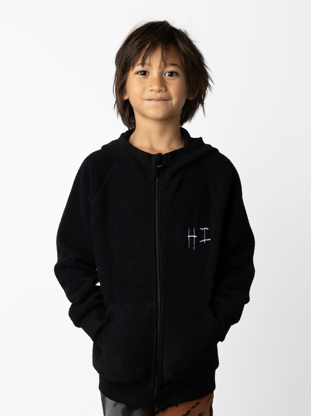 Minti kids clothing. Cosy zip through hoodie with kangaroo pockets for extra warmth! 2x2 rib trim on the hood, cuffs and hem. Small tonal Happy Face embroidery on the front. 330 Gram // Brushed Inside // 95% Cotton // 5% Elastane.