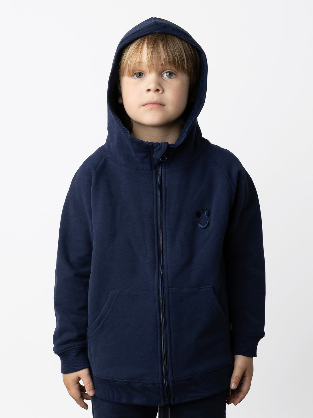 Minti kids clothing. Cosy zip through hoodie with kangaroo pockets for extra warmth! 2x2 rib trim on the hood, cuffs and hem. Small tonal Happy Face embroidery on the front. 330 Gram // Brushed Inside // 95% Cotton // 5% Elastane.