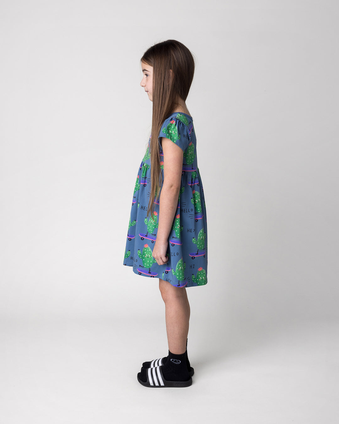 Kid wearing the Skate Cactus Dress in muted blue, side view