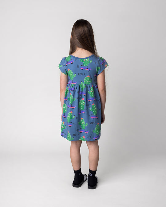 Kid wearing the Skate Cactus Dress in muted blue, back view