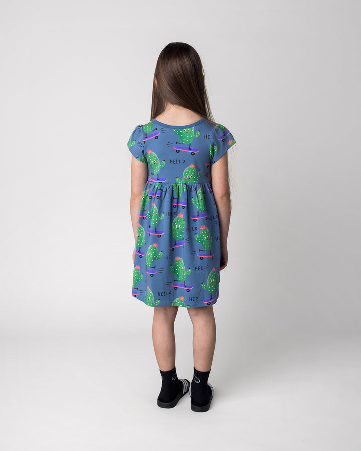 Kid wearing the Skate Cactus Dress in muted blue, back view