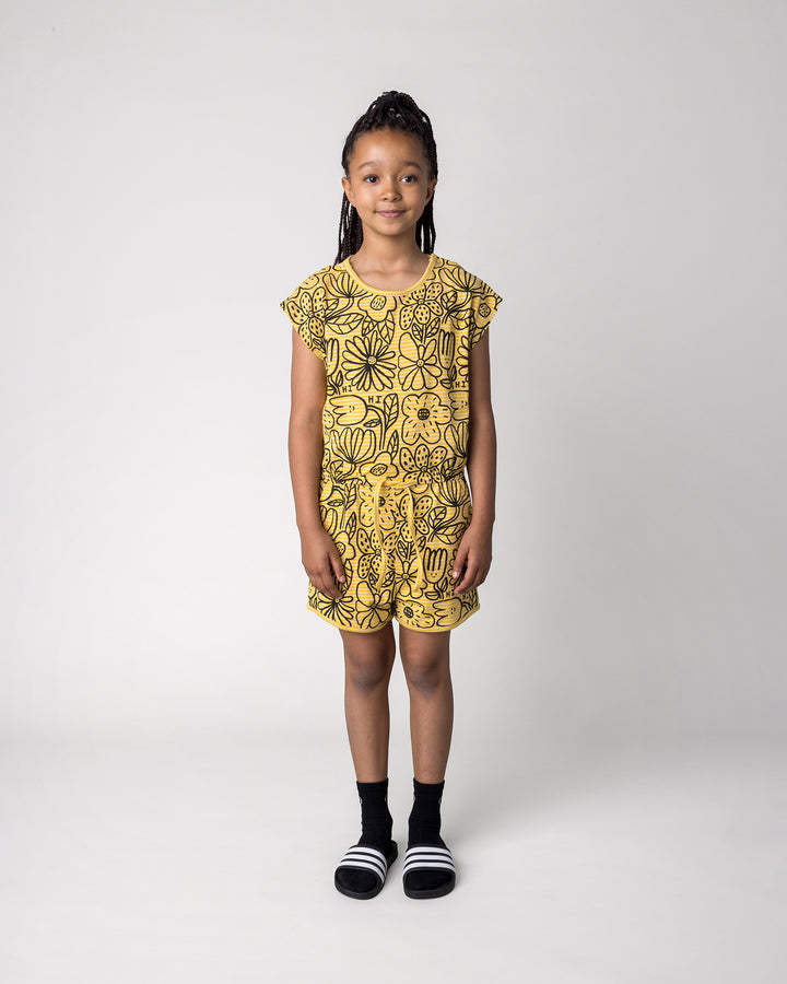 Kid wearing the Big Flowers Playsuit in mustard stripe, front view