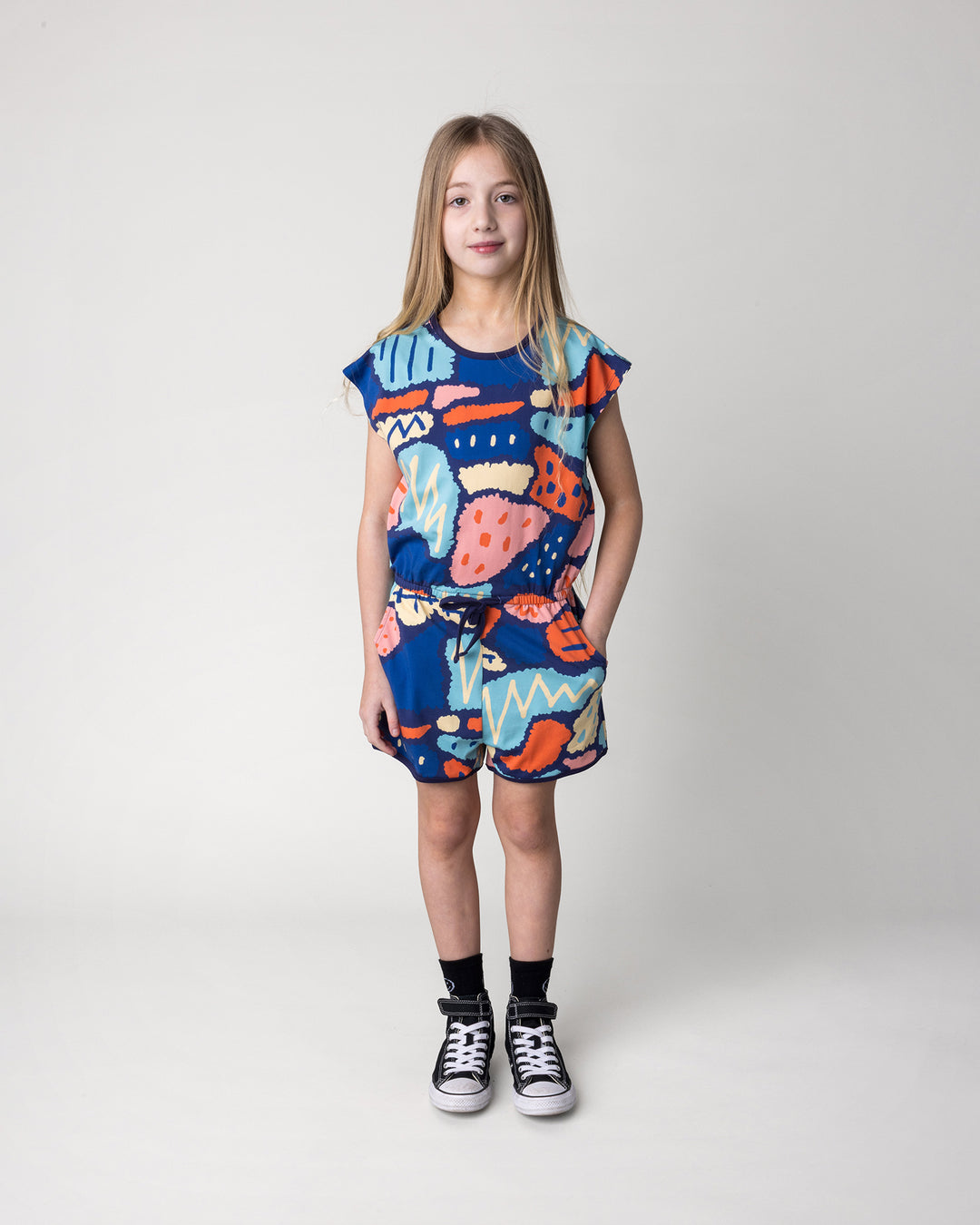 Kid wearing the Cool Shapes Playsuit in dark blue, front view