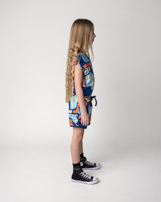 Kid wearing the Cool Shapes Playsuit in dark blue, side view