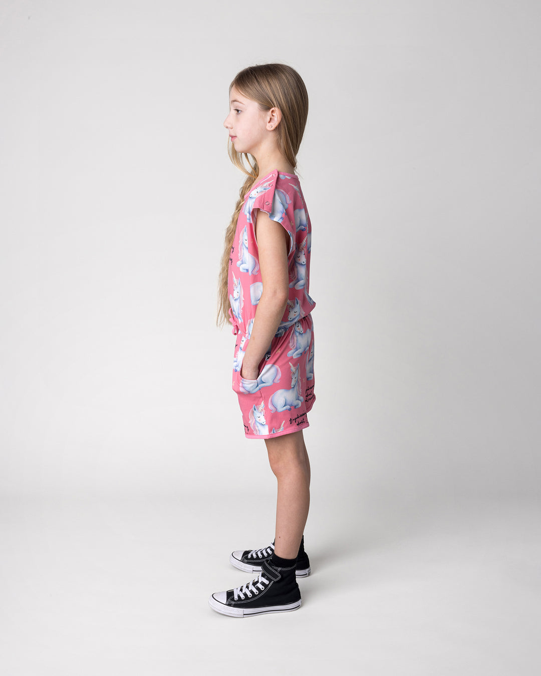 Kid wearing the Daydreaming Unicorn Playsuit in candy, side view