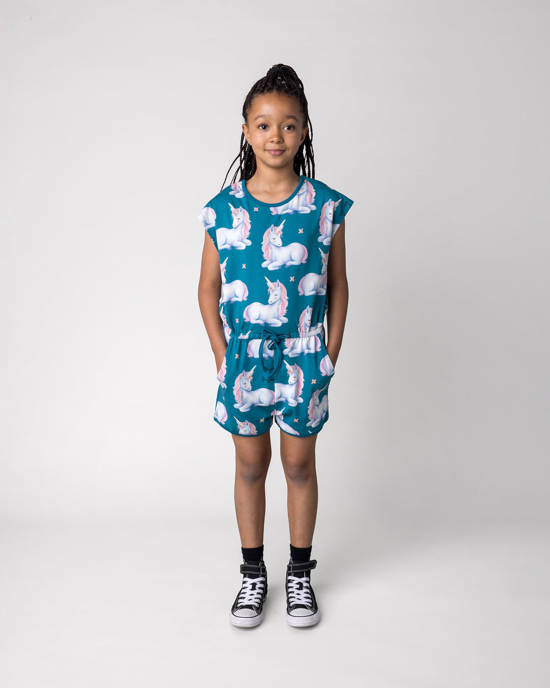 Kid wearing the Daydreaming Unicorn Playsuit in teal, front view