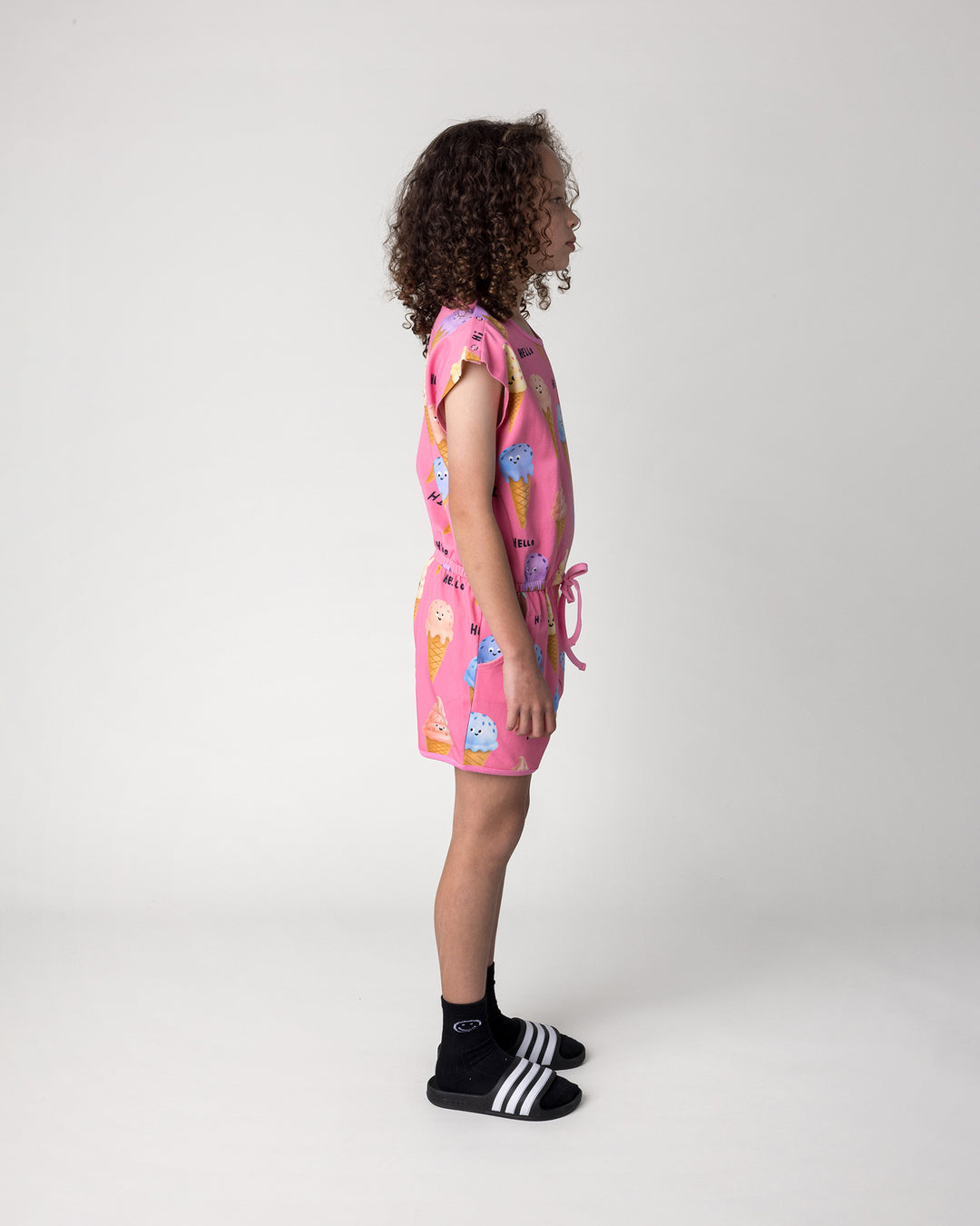 Kid wearing the Happy Icecreams Playsuit in pink, side view