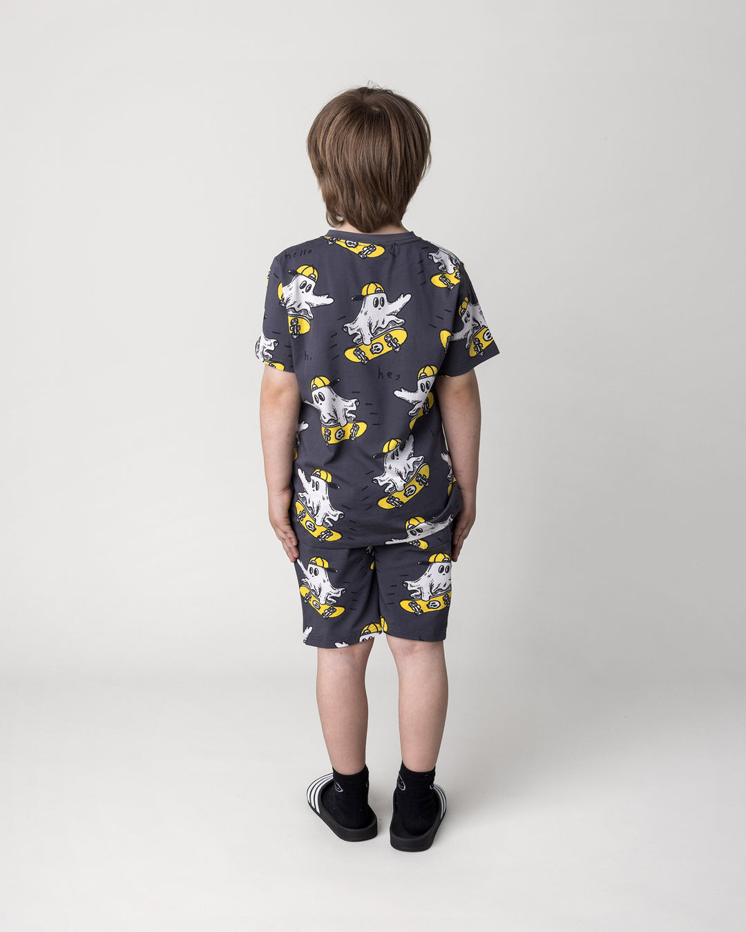 Kid wearing the Skate Ghost Short in dark grey with the Skate Ghost Tee in dark grey, back view