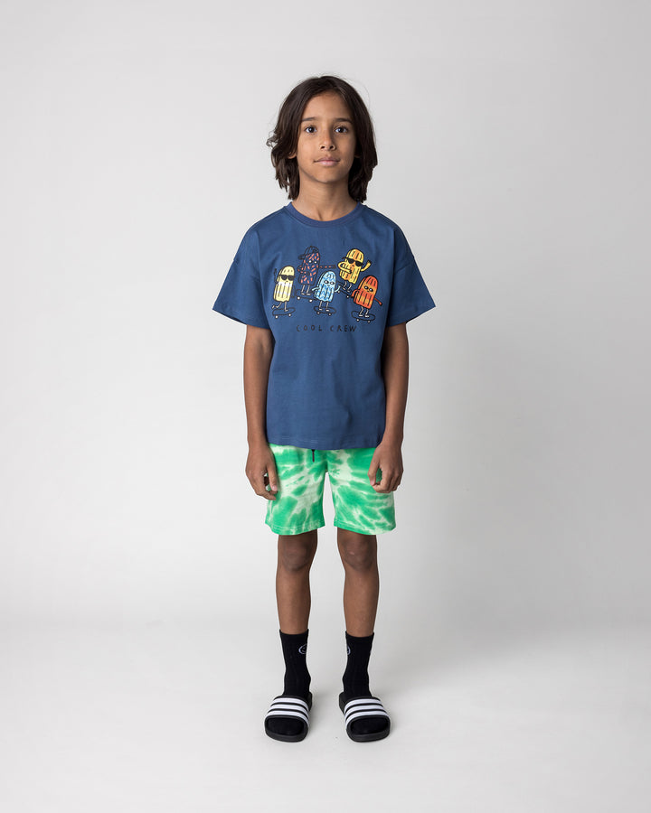 Kid wearing the Splatter Short in green with the Cool Crew Tee in blue, front view