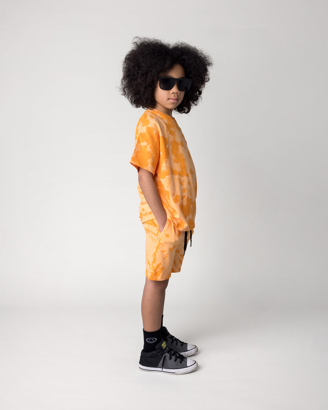 Kid wearing the Splatter Short in orange with the Splatter Tee in orange, side view