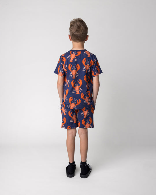 Kid wearing the Vacay Crayfish Short in midnight with the Vacay Crayfish Tee in midnight, back view