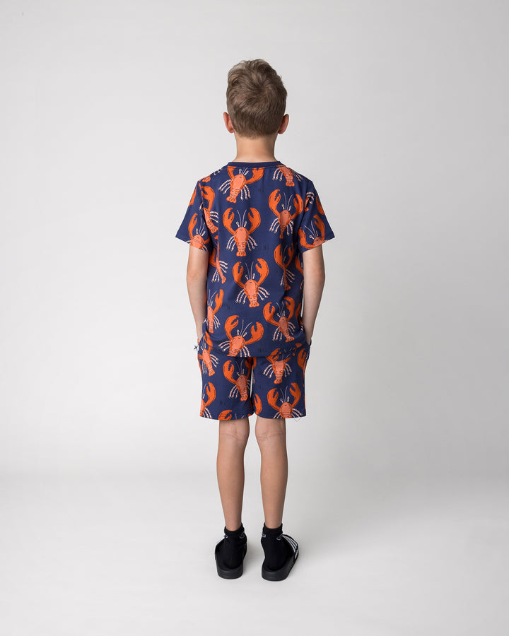 Kid wearing the Vacay Crayfish Short in midnight with the Vacay Crayfish Tee in midnight, back view