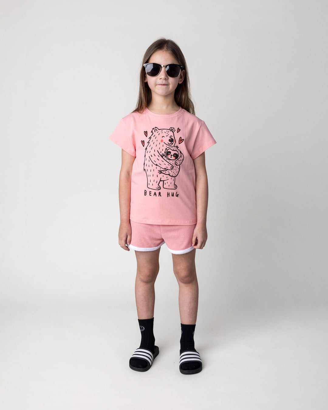 Kid wearing the Bear Hug Tee in pink with the Track Star Short in pink, front view