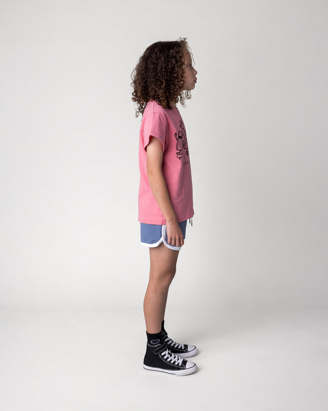 Kid wearing the Cool Crew Tee in candy with the Sprint Short in cornflower and white, side view