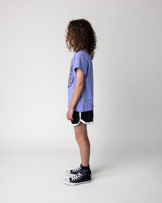 Kid wearing the Chill Sloth Tee in purple with the Sprint Short in black and white, side view