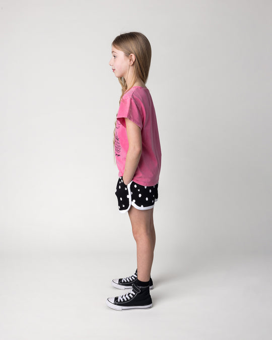 Kid wearing the Different Fruits Tee in pink wash with the Spotty Short in black and white, side view
