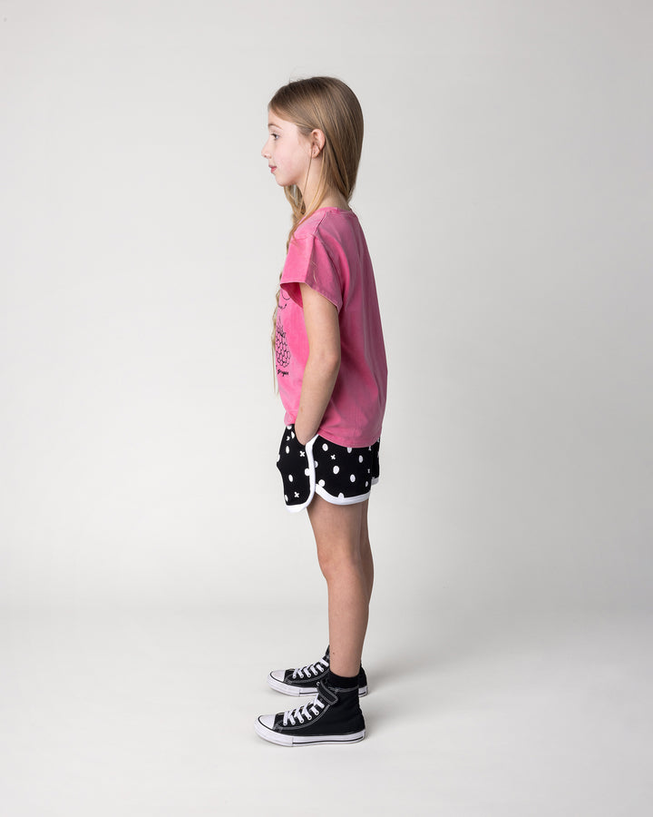 Kid wearing the Different Fruits Tee in pink wash with the Spotty Short in black and white, side view
