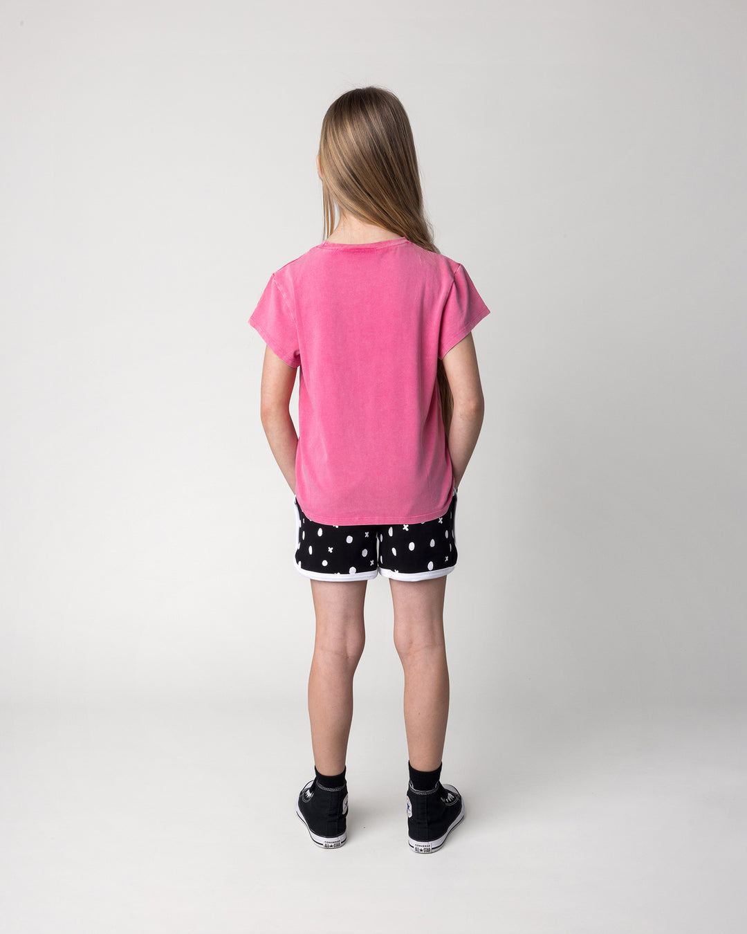 Kid wearing the Different Fruits Tee in pink wash with the Spotty Short in black and white, back view
