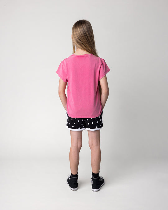Kid wearing the Different Fruits Tee in pink wash with the Spotty Short in black and white, back view