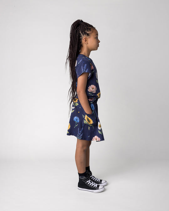 Kid wearing the Flower Friends Tee in ink with the Flower Friends Skirt in ink, side view