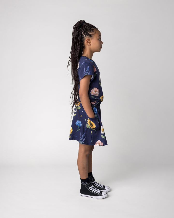 Kid wearing the Flower Friends Tee in ink with the Flower Friends Skirt in ink, side view
