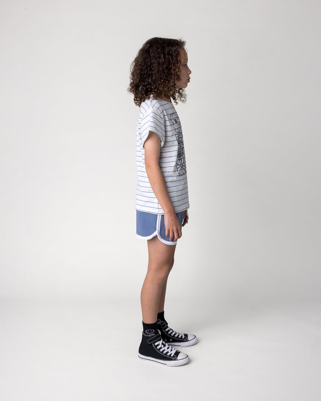 Kid wearing the Flower Party Tee in marle and blue stripe with the Sprint Short in cornflower and white, side view