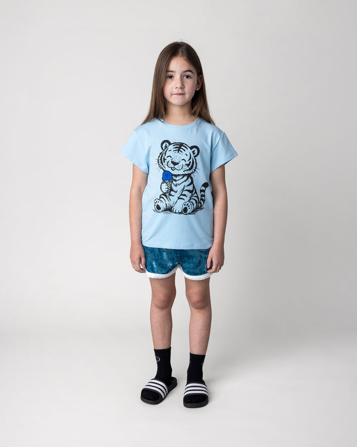 Kid wearing the Happy Tiger Tee in light blue with the Velvet Runner Short in light blue and cream, front view