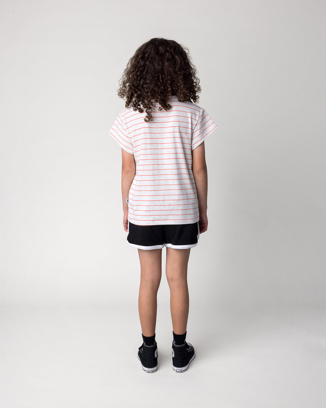 Kid wearing the Happy Tiger Tee in marle and coral stripe with the Sprint Short in black and white, back view