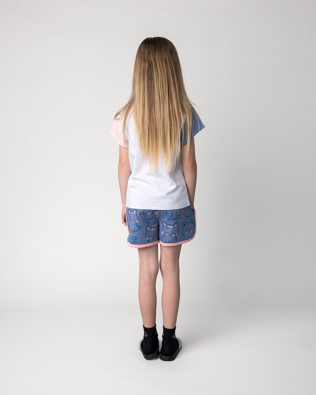 Kid wearing the Hi Cat Bear Tee in white marle, blue and pink with the Hi Cat Bear Short in cornflower and pink, back view