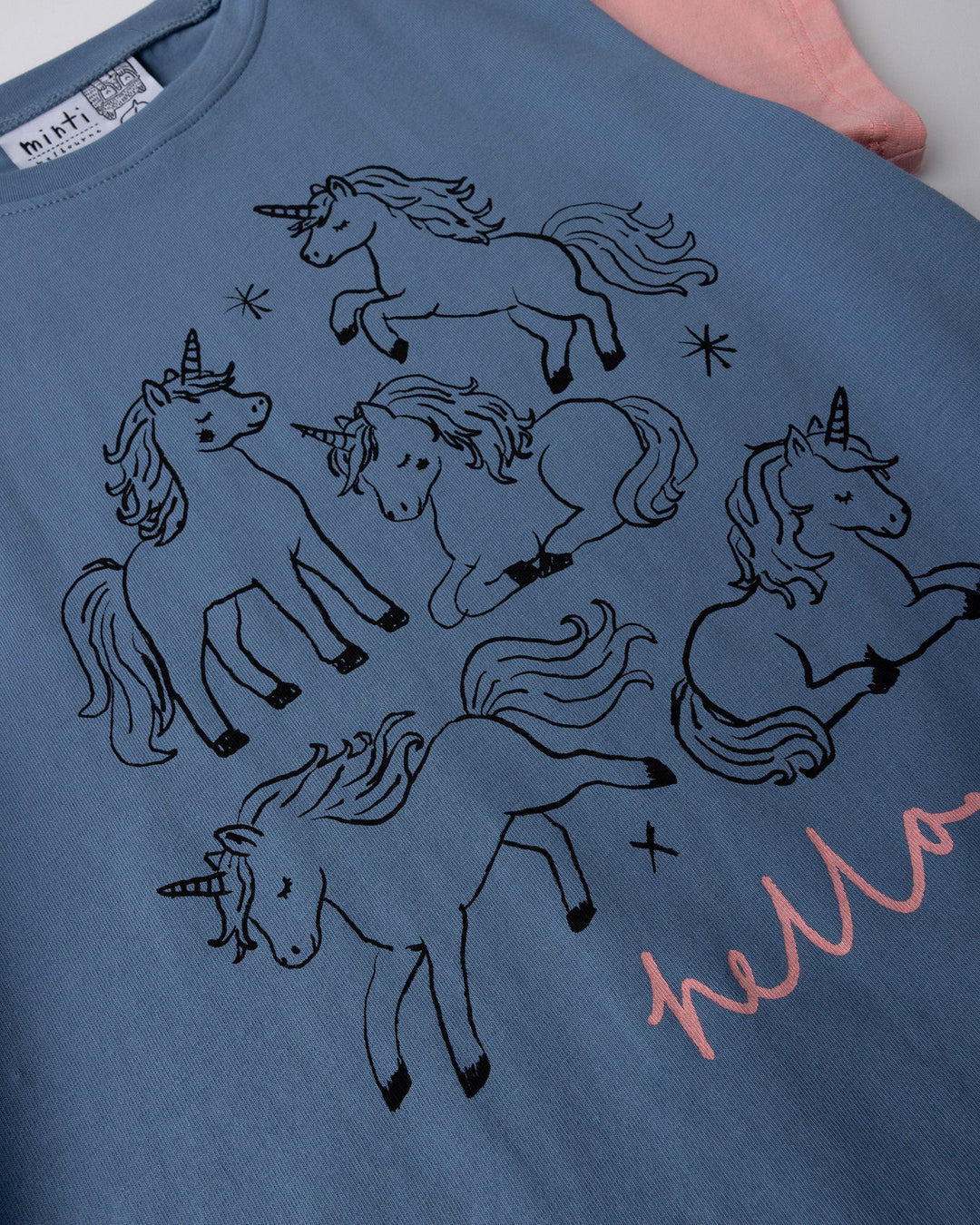 Close up of the Hello Unicorns Tee print in mid blue, light blue and pink
