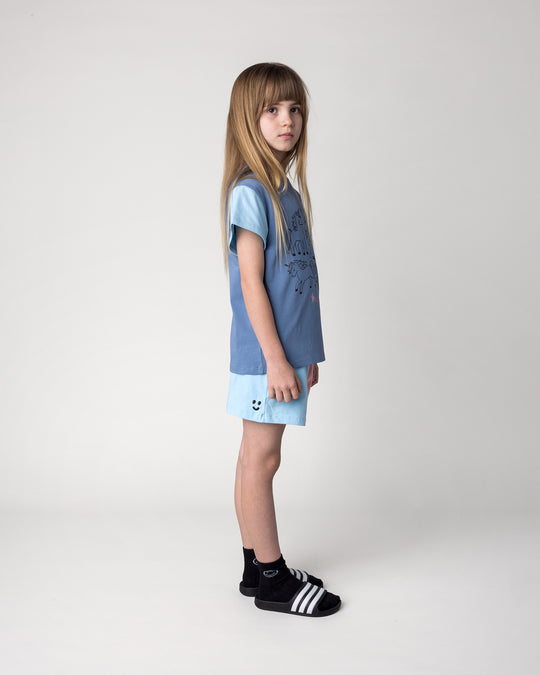 Kid wearing the Hello Unicorns Tee in mid blue, light blue and pink with the Two Tone Short in light blue and pink, side view