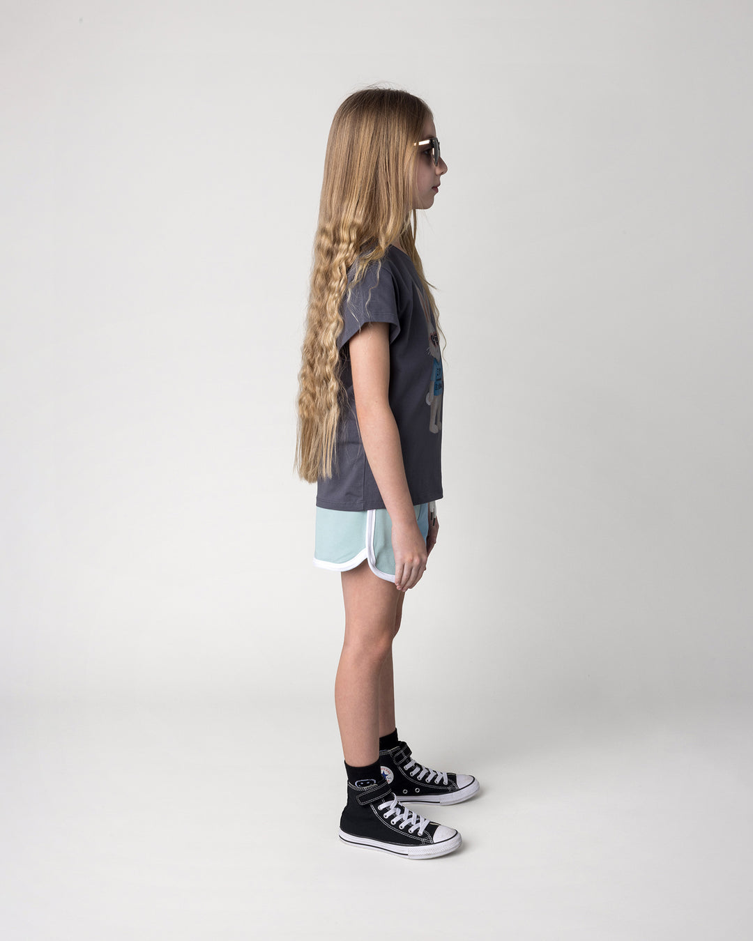 Kid wearing the Icecream Bunny Tee in dark grey with the Sprint Short in mint, aqua and lilac, side view