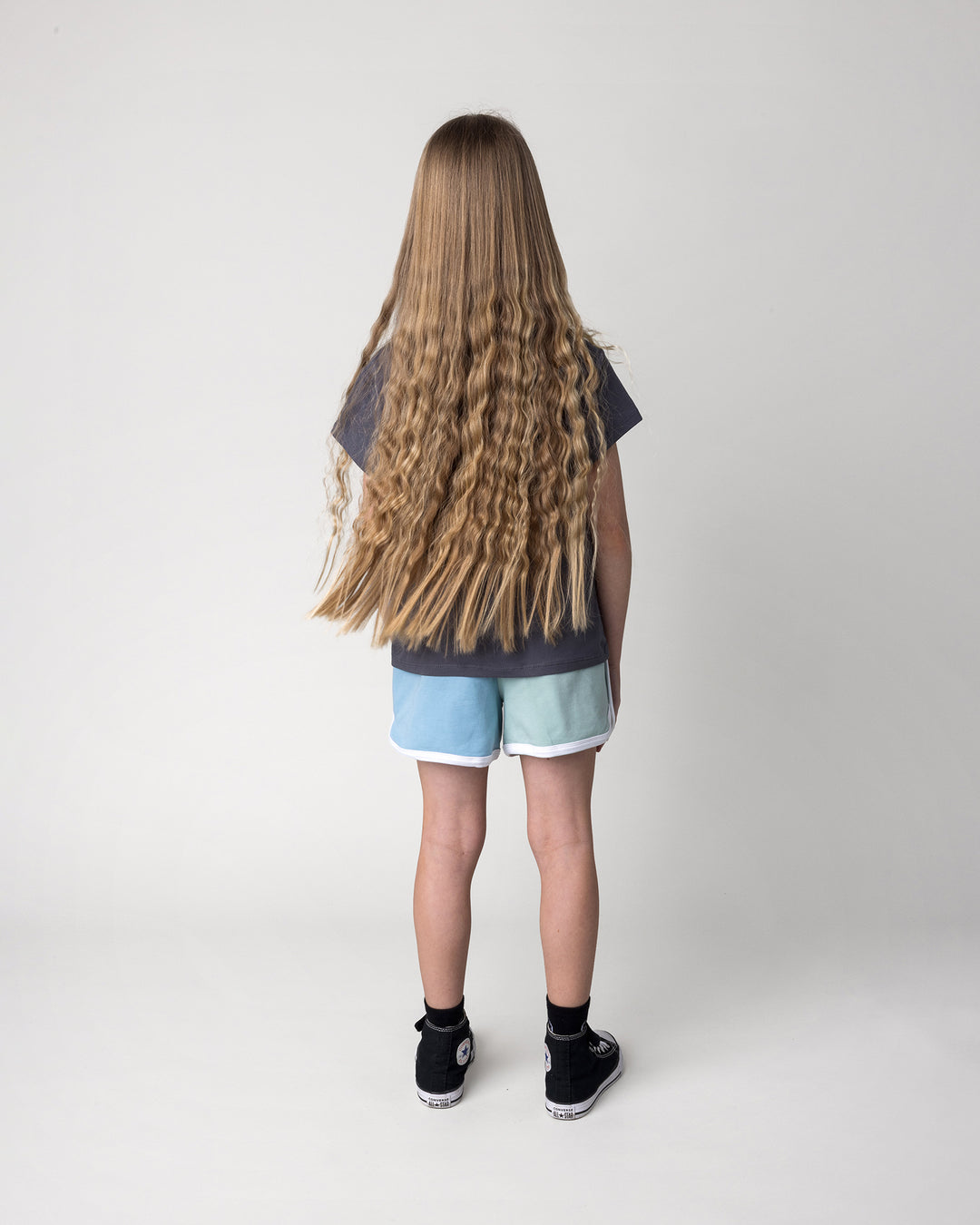 Kid wearing the Icecream Bunny Tee in dark grey with the Sprint Short in mint, aqua and lilac, back view